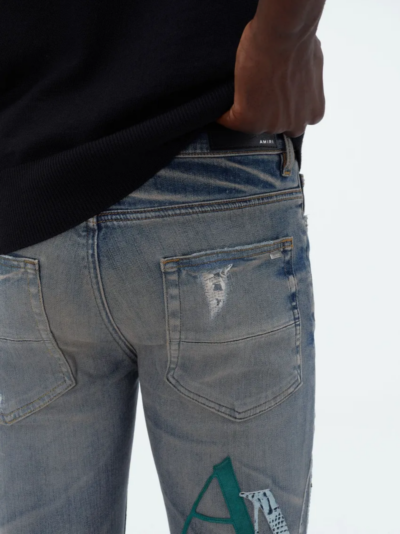 AMIRI STAGGERED LOGO JEANS INDIGO
